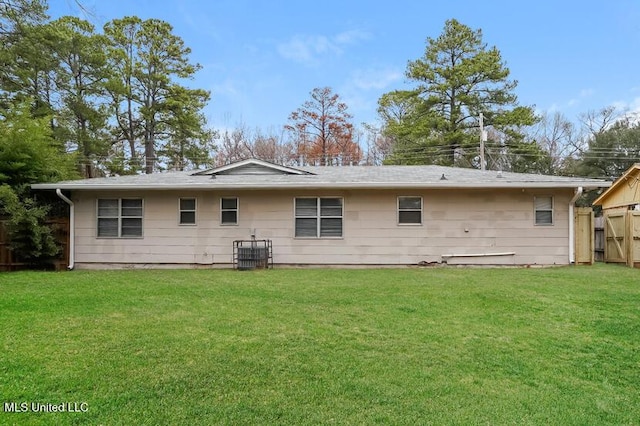 rear view of property featuring a yard and fence