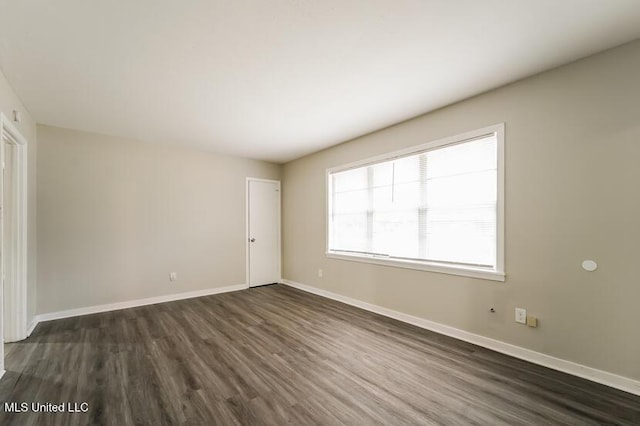 empty room featuring baseboards and dark wood-style flooring