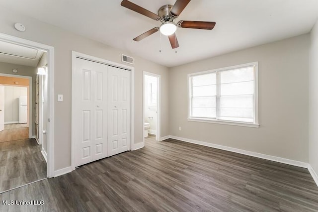 unfurnished bedroom with dark wood-type flooring, baseboards, visible vents, and a closet