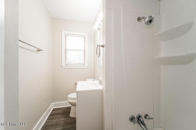 bathroom with vanity, wood finished floors, baseboards, a shower, and toilet