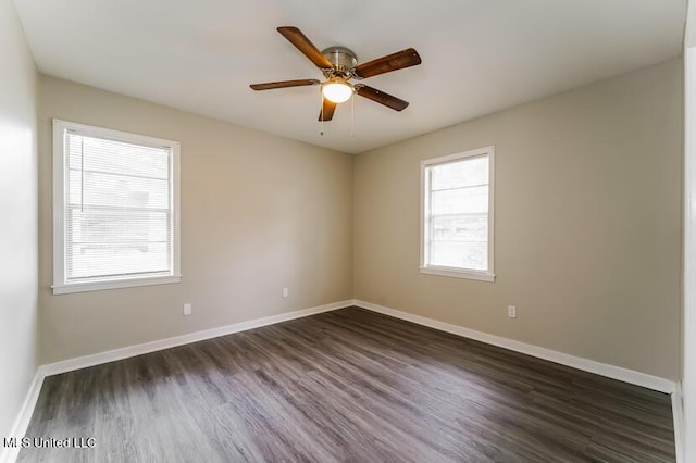 spare room with baseboards, dark wood-style floors, and a ceiling fan