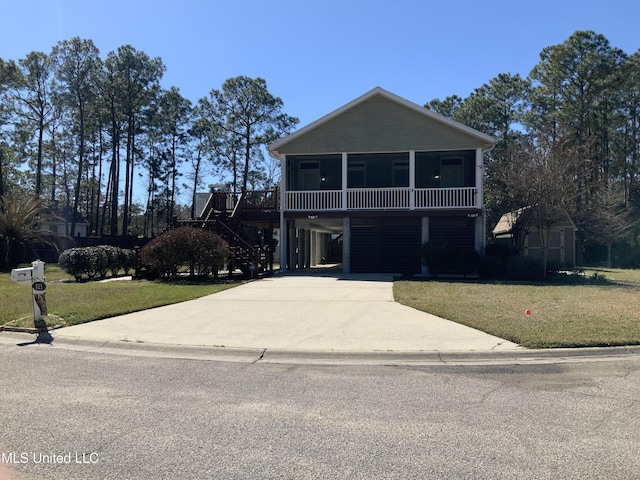 view of front of house featuring an outbuilding, a sunroom, a carport, driveway, and a front lawn