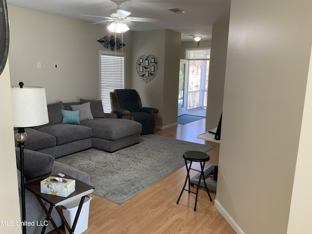 living area featuring ceiling fan, light wood finished floors, visible vents, and baseboards