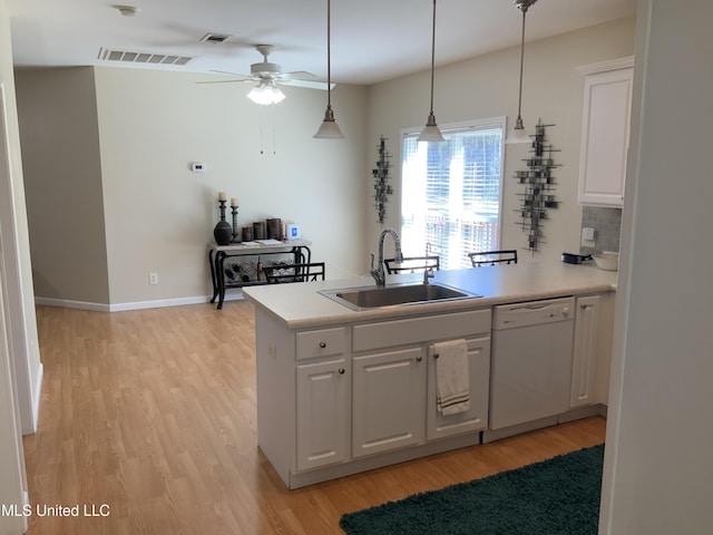 kitchen featuring a sink, light wood-type flooring, a peninsula, and dishwasher