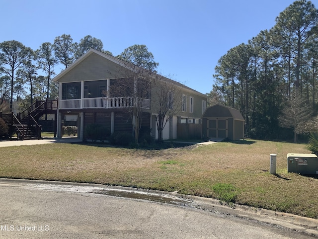 view of front of home featuring an outbuilding, a sunroom, stairs, a shed, and a front lawn