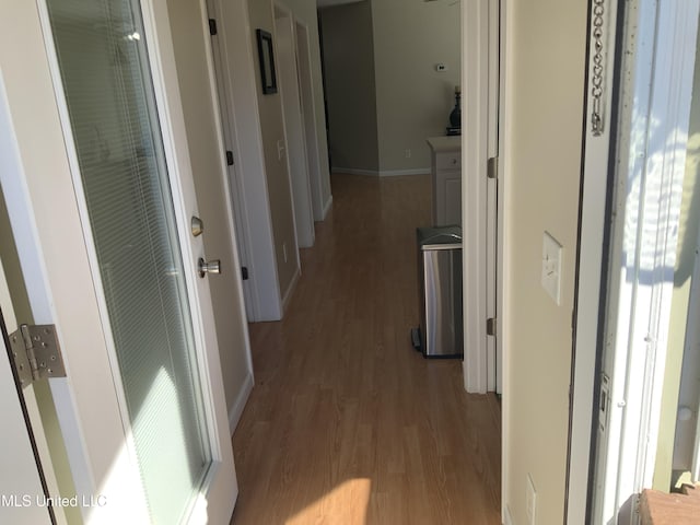 hall featuring light wood-style floors and baseboards