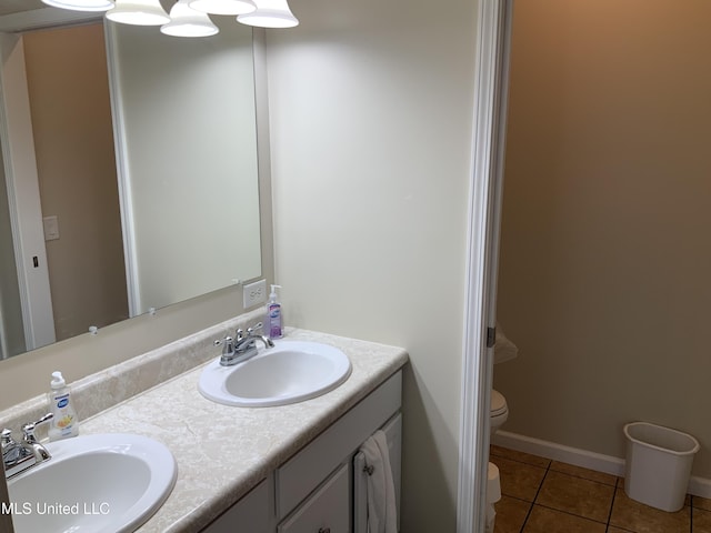 full bathroom featuring toilet, double vanity, a sink, and tile patterned floors