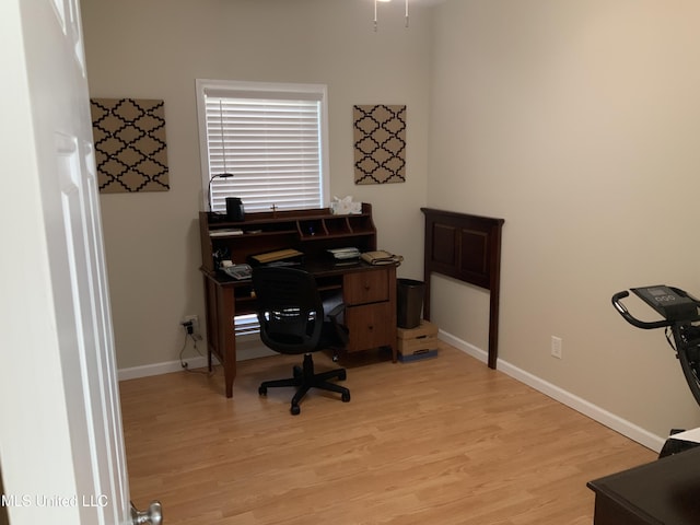 home office with light wood-style flooring and baseboards