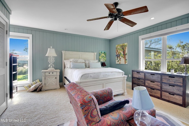 bedroom with light carpet, ceiling fan, and wood walls