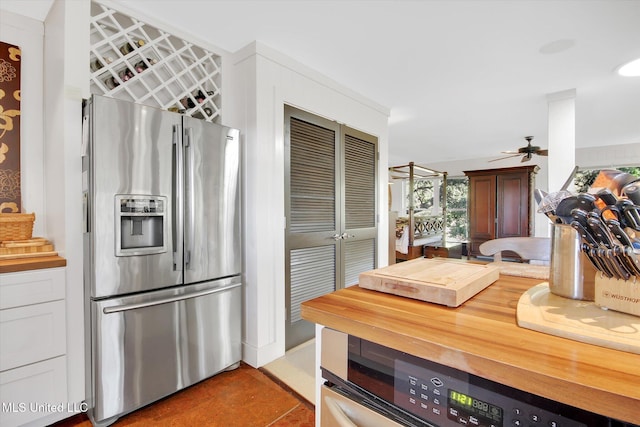 kitchen featuring tile patterned flooring, ceiling fan, stainless steel refrigerator with ice dispenser, and wooden counters