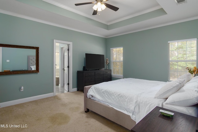 bedroom featuring ceiling fan, a raised ceiling, ensuite bathroom, light carpet, and ornamental molding