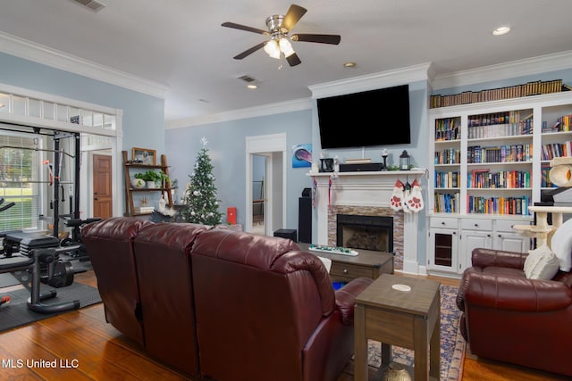 living room with a stone fireplace, crown molding, ceiling fan, and wood-type flooring