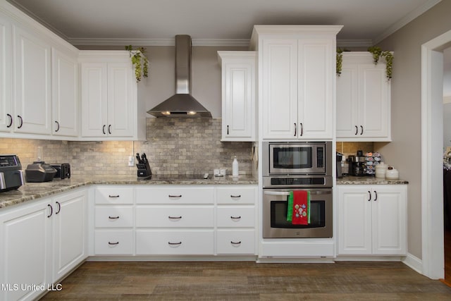 kitchen featuring dark hardwood / wood-style flooring, white cabinets, wall chimney range hood, and appliances with stainless steel finishes