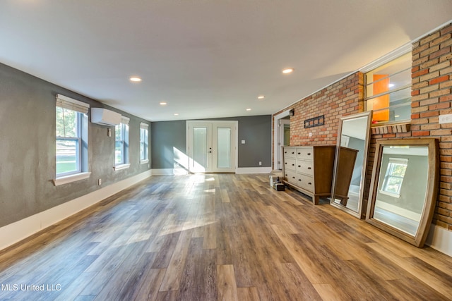 unfurnished living room featuring hardwood / wood-style flooring and a wall mounted AC