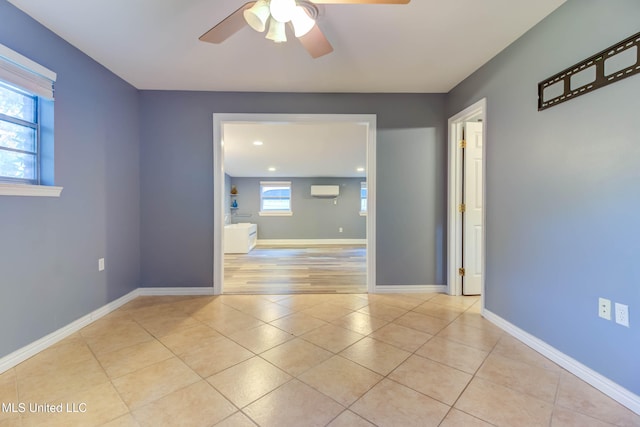 unfurnished room with ceiling fan, an AC wall unit, a wealth of natural light, and light hardwood / wood-style flooring