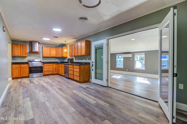 kitchen with appliances with stainless steel finishes, light wood-type flooring, and wall chimney range hood