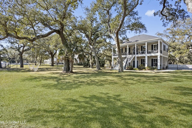 view of yard with stairs, covered porch, and fence