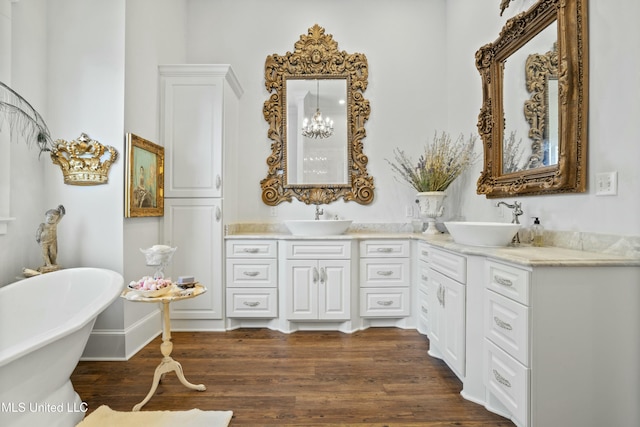 full bath featuring a freestanding bath, double vanity, wood finished floors, and a sink