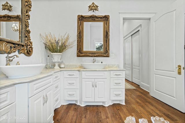 full bath featuring double vanity, a sink, and wood finished floors