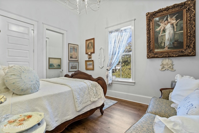 bedroom with an inviting chandelier, wood finished floors, and baseboards