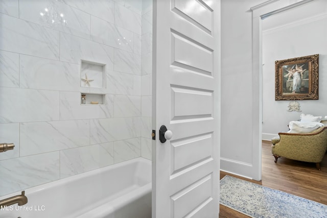 bathroom with ornamental molding, bathtub / shower combination, baseboards, and wood finished floors