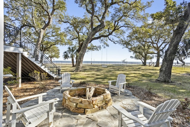 view of patio / terrace featuring a fire pit, fence, and stairway