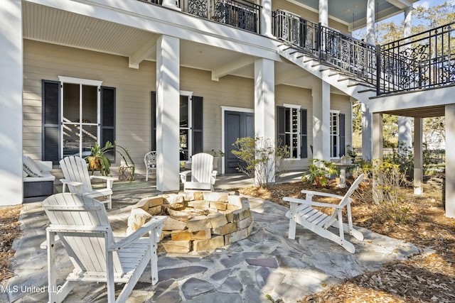 view of patio with an outdoor fire pit and a balcony