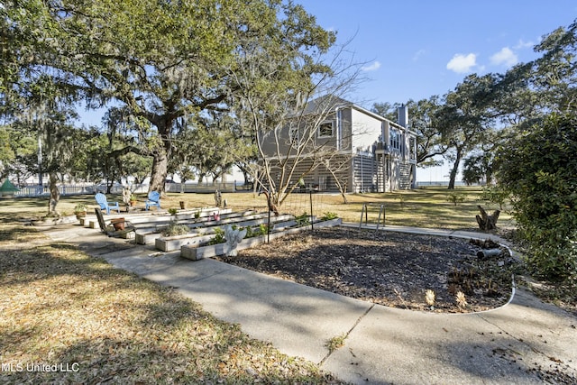 view of community with stairs, a lawn, and a garden