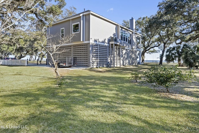 view of side of home featuring a chimney, stairway, and a lawn