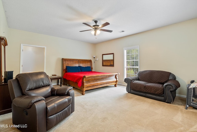 bedroom with ceiling fan, light carpet, and a textured ceiling