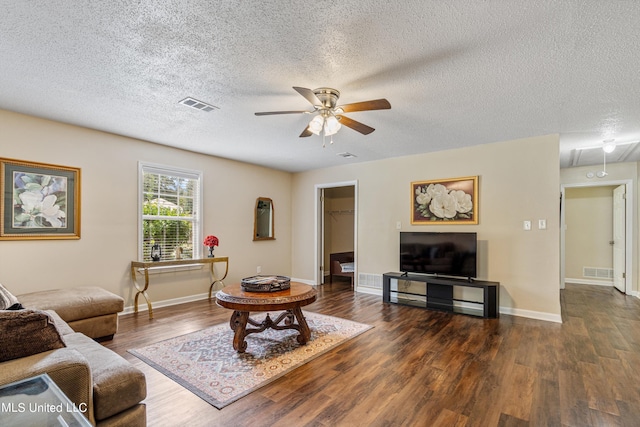 living room featuring dark wood-type flooring, ceiling fan, and a textured ceiling