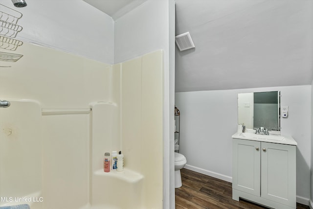 bathroom featuring lofted ceiling, hardwood / wood-style flooring, a shower, toilet, and vanity