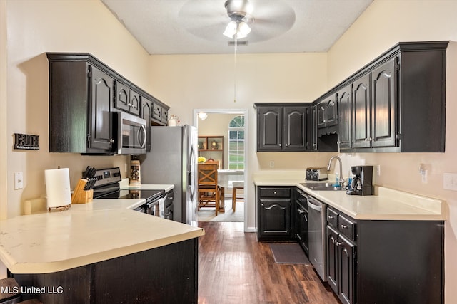 kitchen with kitchen peninsula, ceiling fan, appliances with stainless steel finishes, dark hardwood / wood-style floors, and sink