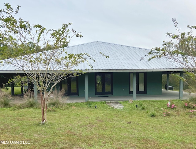 back of property with french doors, a patio, a yard, and metal roof