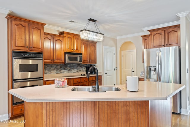 kitchen with appliances with stainless steel finishes, sink, an island with sink, and light hardwood / wood-style flooring