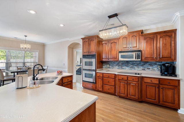 kitchen featuring appliances with stainless steel finishes, hanging light fixtures, sink, an inviting chandelier, and light hardwood / wood-style flooring