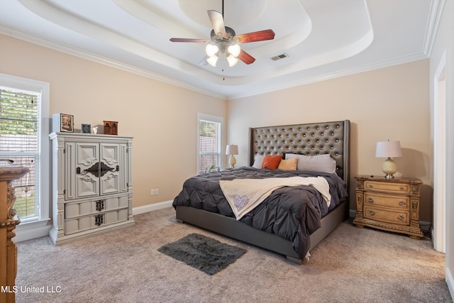 bedroom with ornamental molding, ceiling fan, multiple windows, and a tray ceiling