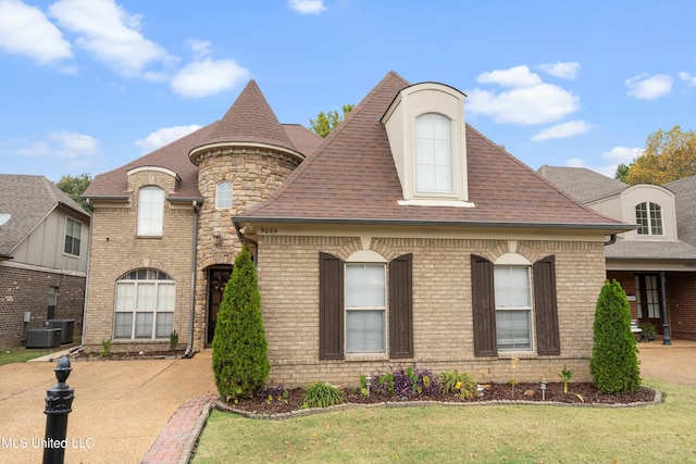 french country inspired facade with central air condition unit and a front yard