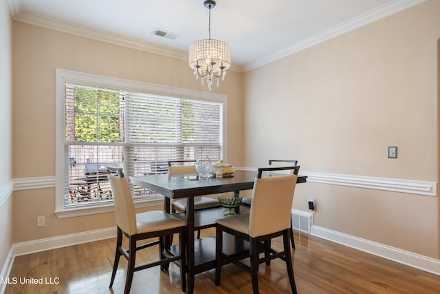 dining room featuring wood-type flooring, a healthy amount of sunlight, a chandelier, and ornamental molding