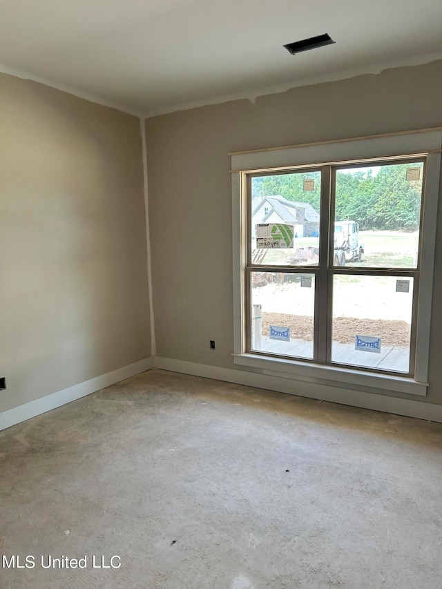 empty room with plenty of natural light, visible vents, concrete flooring, and baseboards