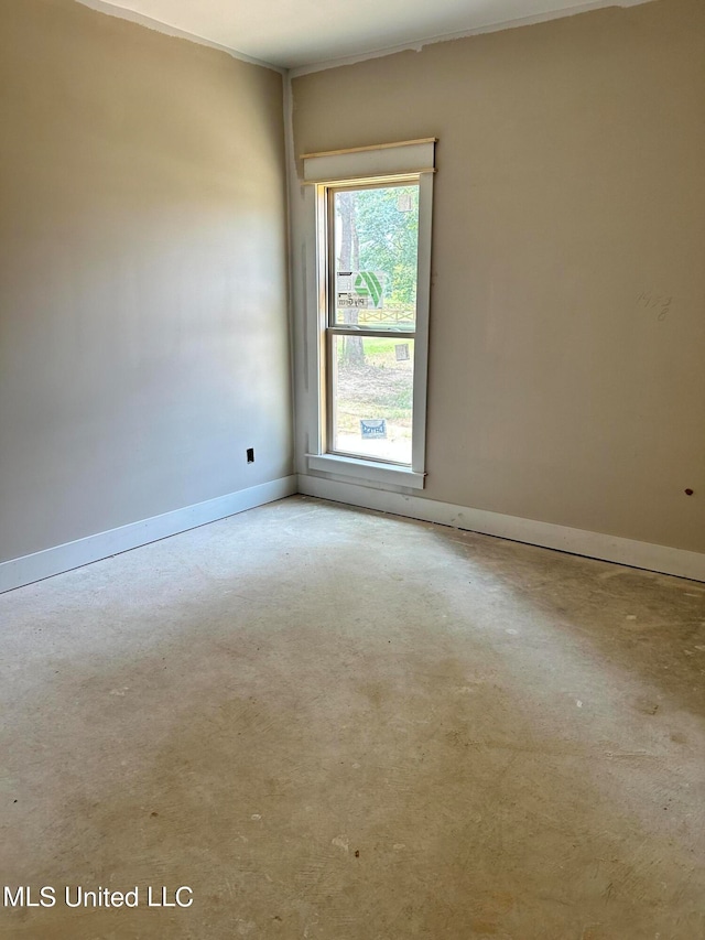 spare room featuring baseboards and concrete floors