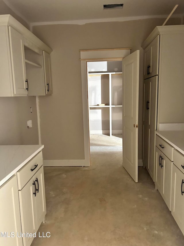 kitchen with visible vents, white cabinetry, unfinished concrete floors, and light countertops