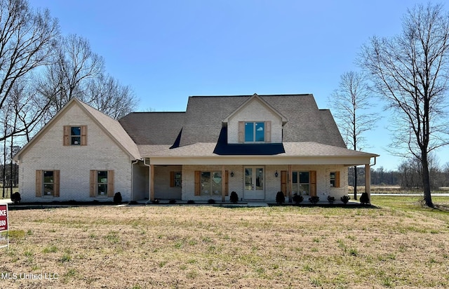 view of front facade featuring brick siding, covered porch, and a front yard