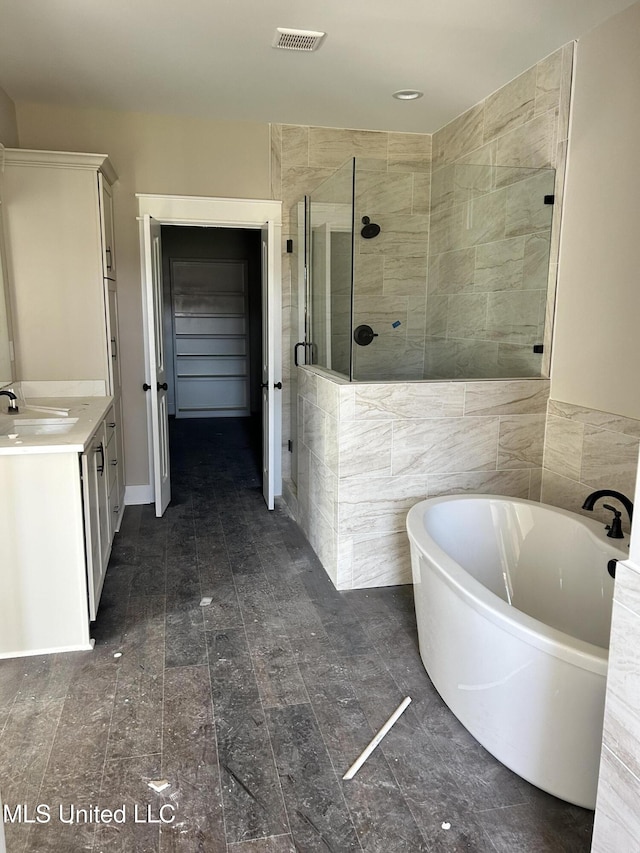 bathroom with vanity, visible vents, a freestanding bath, a shower stall, and a walk in closet