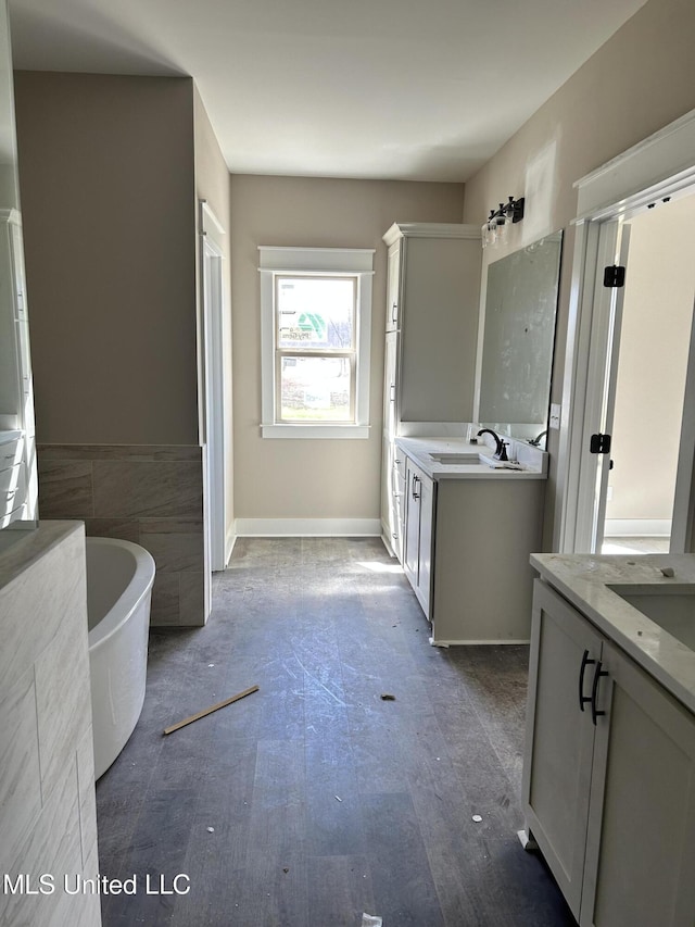 bathroom with a sink, a freestanding tub, tile walls, and two vanities