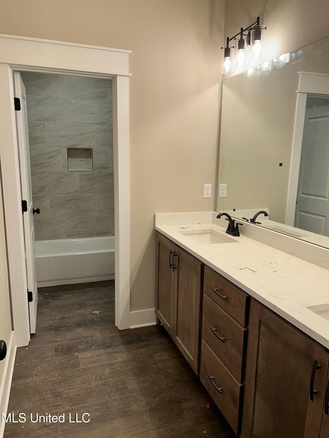 full bathroom featuring double vanity, wood finished floors, baseboards, and a sink