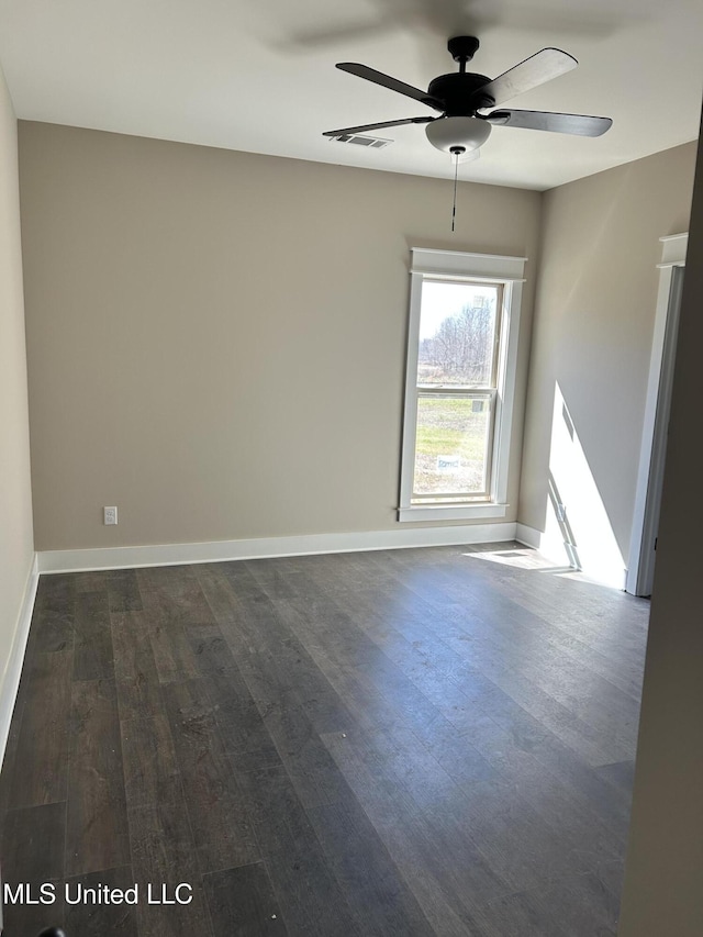 empty room featuring dark wood finished floors, baseboards, visible vents, and ceiling fan