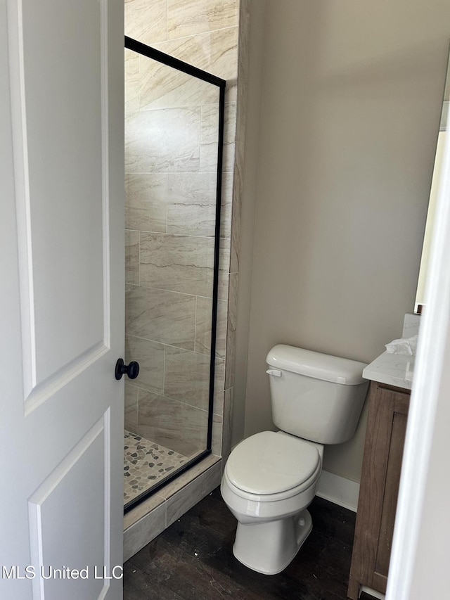 full bath featuring toilet, a stall shower, wood finished floors, baseboards, and vanity