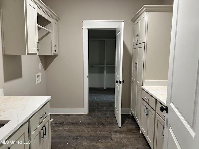 interior space featuring baseboards, light stone countertops, and dark wood-type flooring