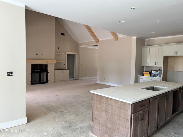 kitchen with light stone counters, a kitchen island, white cabinetry, concrete flooring, and vaulted ceiling